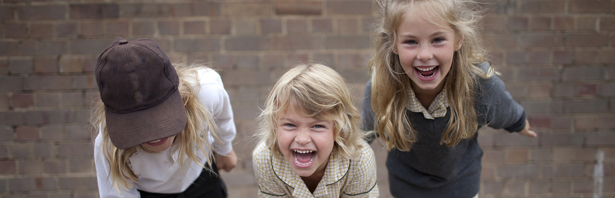 Three young school kids laughing in a school yard