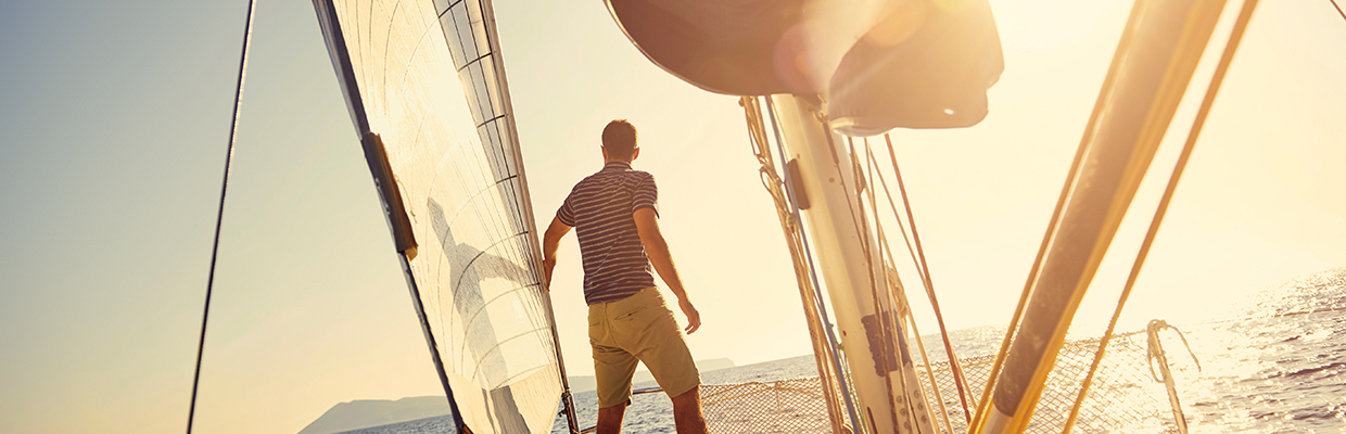 Man in shorts and t-shirt on bow of a sailing boat